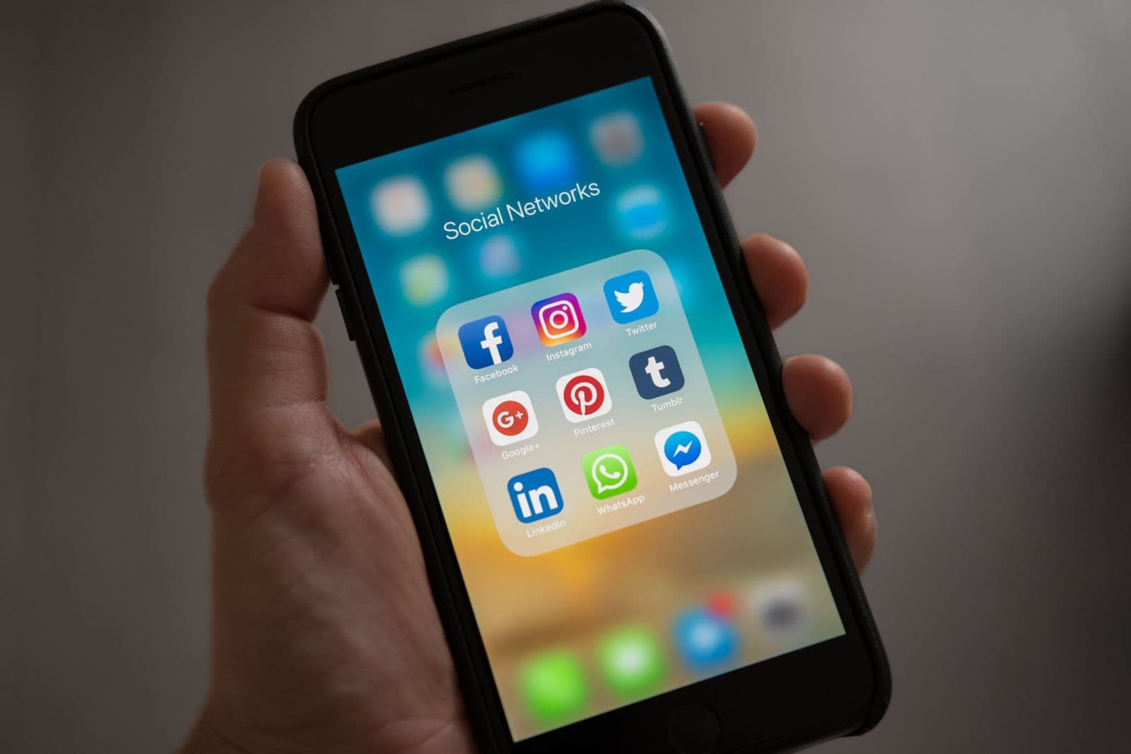 Hand holding a phone open to social network apps